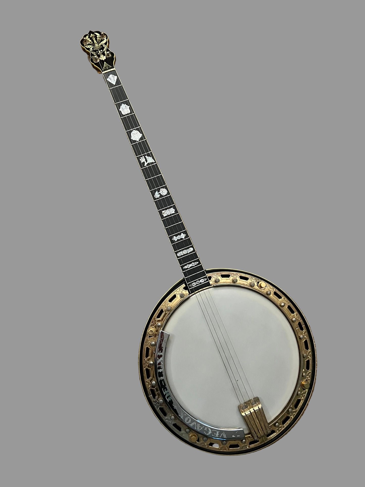 A Banjo guitar with a black body, gold-toned rim, white soundboard, and black-and-white inlaid neck, photographed from above on a brown textured carpet.