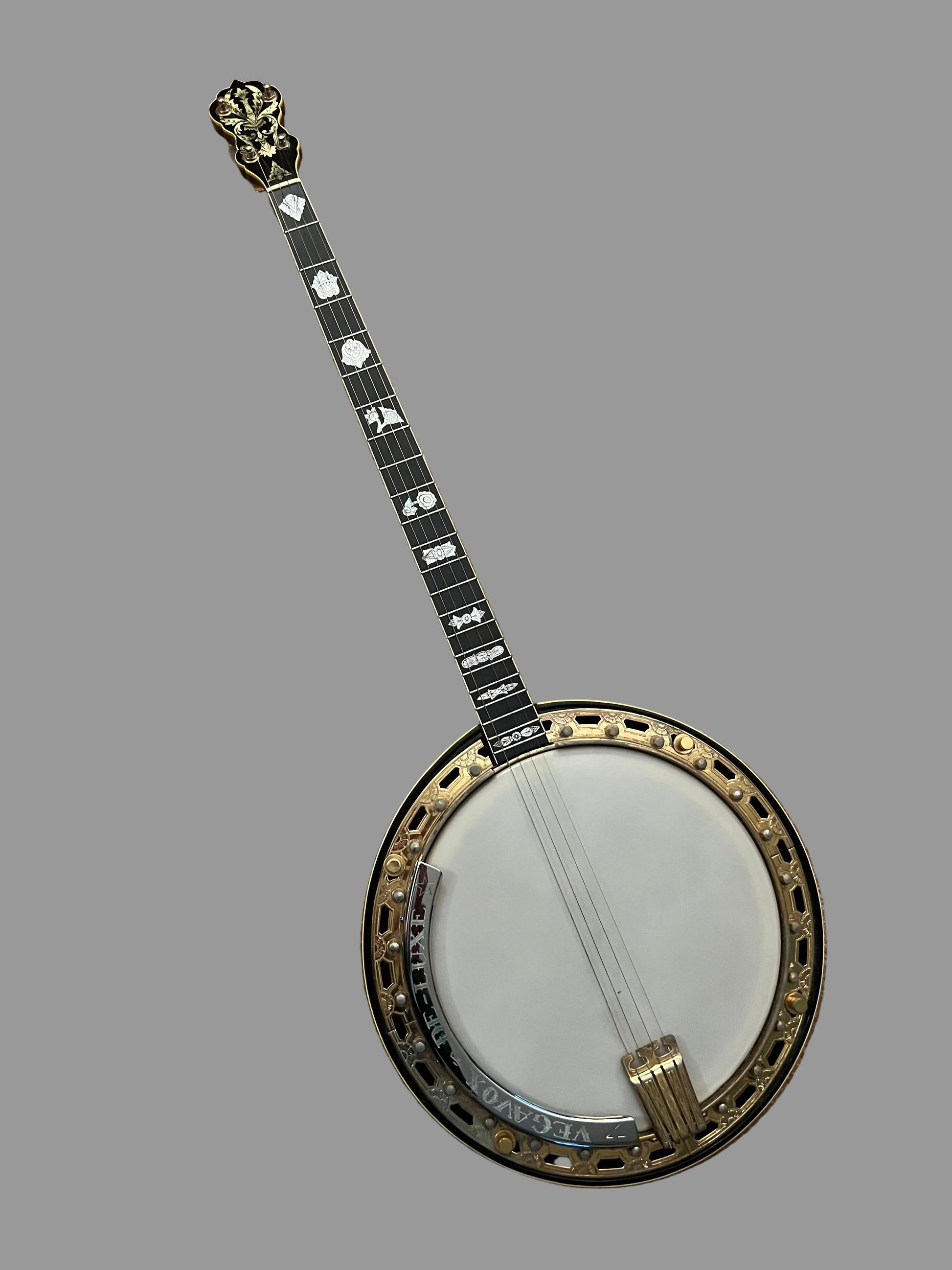 A Banjo guitar with a black body, gold-toned rim, white soundboard, and black-and-white inlaid neck, photographed from above on a brown textured carpet.